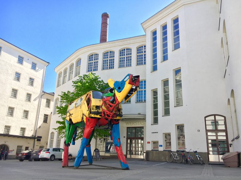 A large, colourful statue in a square surrounded by white houses